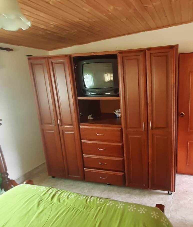 Armario clóset de madera estilo clásico en color caoba, con puertas de diseño en relieve, cajones centrales y espacio abierto para televisor.