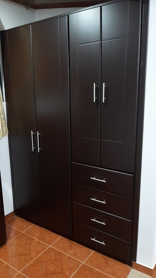 Clóset de madera estilo moderno en color wengué oscuro, con puertas lisas y manijas metálicos plateados, combinado con cajones verticales.