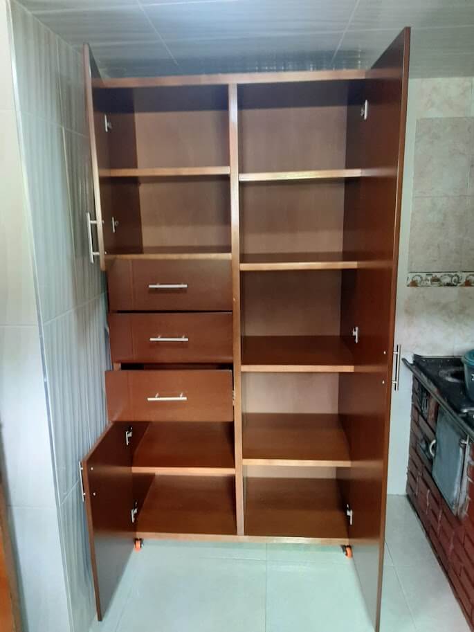 Clóset de madera color nogal con acabado mate, diseño moderno de puertas lisas, múltiples estantes abiertos, tres cajones y compartimientos inferiores, con manijas metálicas rectas.