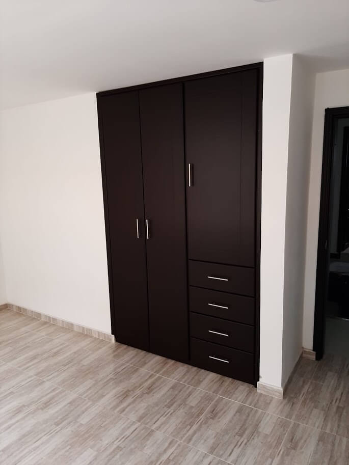 Clóset empotrado de madera en tono wengué oscuro, con diseño moderno minimalista, cuatro cajones y puertas lisas, equipado con manijas metálicas rectas.