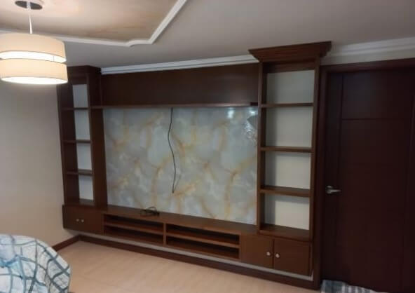 Centro de entretenimiento empotrado en madera tono caoba, con repisas laterales abiertas, puertas inferiores y espacio central