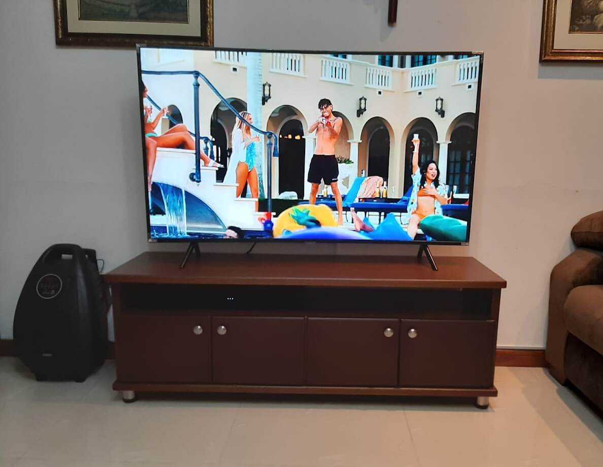 Mueble bajo de madera en color caoba con superficie plana para televisor, compartimientos con puertas de madera y tiradores metálicos redondos