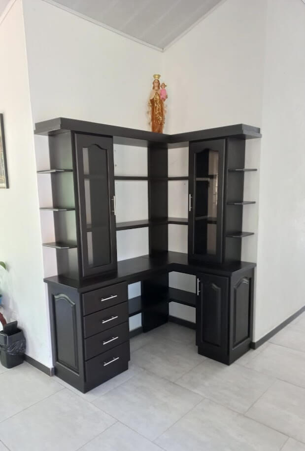 Biblioteca esquinera de madera en color wengué con diseño moderno, repisas abiertas, puertas de vidrio, cajones con manijas metálicas y compartimientos inferiores